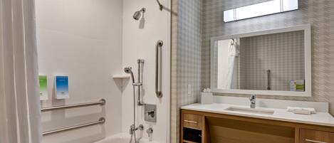 Un baño moderno con bañera, ducha, tocador con espejo y barra para toallas.