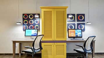 A modern office space with two desks, two office chairs, and a large yellow cabinet.