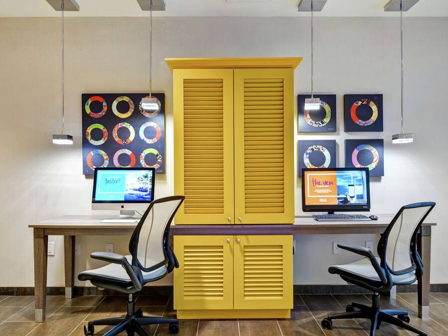 A modern office space with two desks, two office chairs, and a large yellow cabinet.