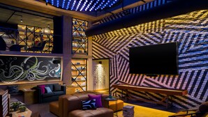 A modern lounge area with a sofa, a table, and a stack of wooden blocks. - Moxy San Diego Downtown/Gaslamp Quarter (San Diego)