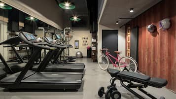 Ein Fitnessraum mit Laufbändern, Ergometer und einer Langhantelbank.