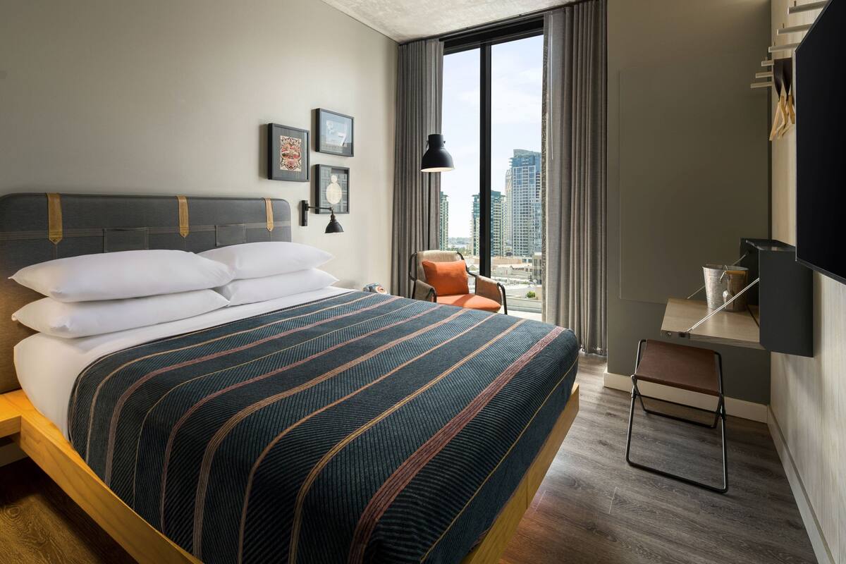 Habitación de hotel moderna con una cama grande, un escritorio y vistas a la ciudad.