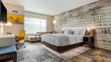 Una habitación de hotel moderna con una cama grande, un escritorio, una silla y un televisor.