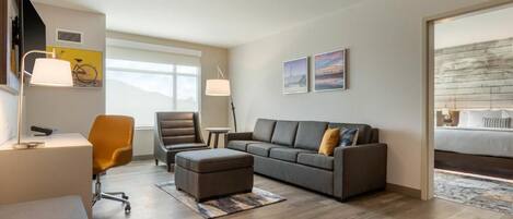 Une chambre d’hôtel moderne équipée d’un canapé, d’un fauteuil, d’un bureau et d’un lit.