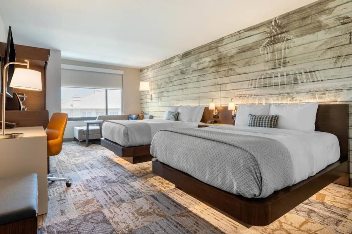 A hotel room with a large bed, a desk, and a chair.