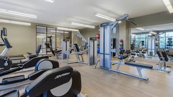 A gym with treadmills, weight machines, and a mirrored wall.