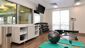 A fitness room with exercise equipment, a television, and a window. - Holiday Inn Express Alliance by IHG (Alliance)