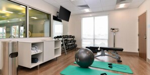 A fitness room with exercise equipment, a television, and a window. - Holiday Inn Express Alliance by IHG (Alliance)