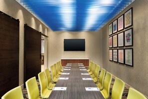 A conference room with a long table, yellow chairs, a flat-screen TV, and framed artwork on the wall. - Holiday Inn Express Alliance by IHG (Alliance)