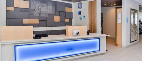 Una recepción de diseño moderno, con un reloj y carteles informativos en la pared.