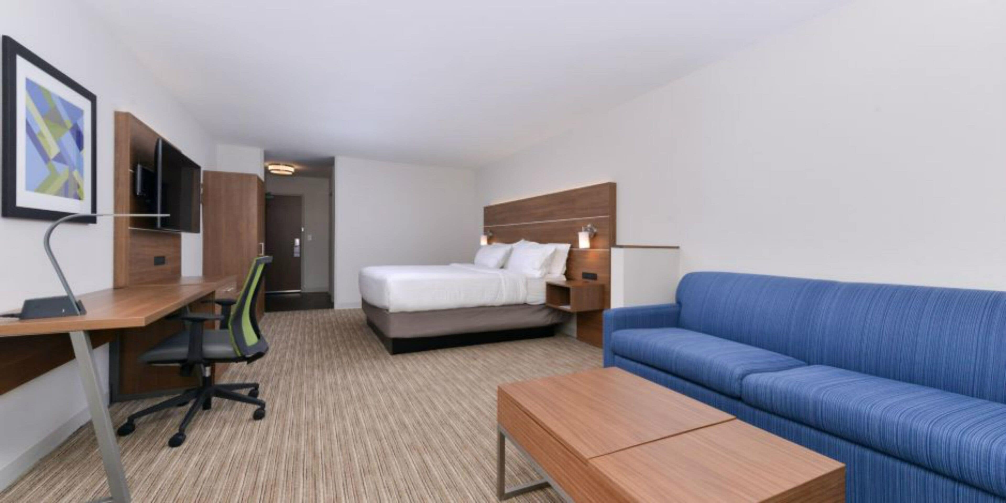 A hotel room with a bed, a desk with a chair, a sofa, and a coffee table.