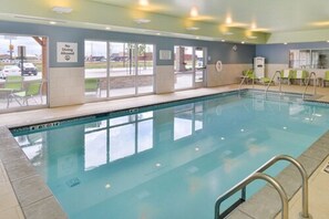 An indoor swimming pool with clear glass walls, a no diving allowed sign, and a view of the parking lot outside. - Holiday Inn Express Alliance by IHG (Alliance)