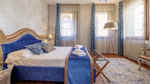 A bedroom with a large bed, a chandelier, and a floor lamp. - Casa Verona (Venice)