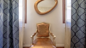 A room with a patterned curtain, a wall-mounted oval mirror, and a classic armchair. - Casa Verona (Venice)
