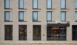 Um hotel com fachada moderna de tijolos, janelas amplas e uma placa destacada com a inscrição 'hotel INDIGO'.