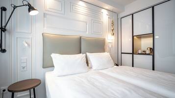 A neatly arranged hotel room with a bed, bedside lamp, and a small table.