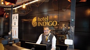 A hotel reception desk with a digital screen, a guest card reader, and a sign for hotel Indigo. - Hotel Indigo Dresden - Wettiner Platz by IHG (Dresden)