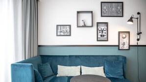 A modern living room with a blue sofa, a round coffee table, and framed artwork on the wall.