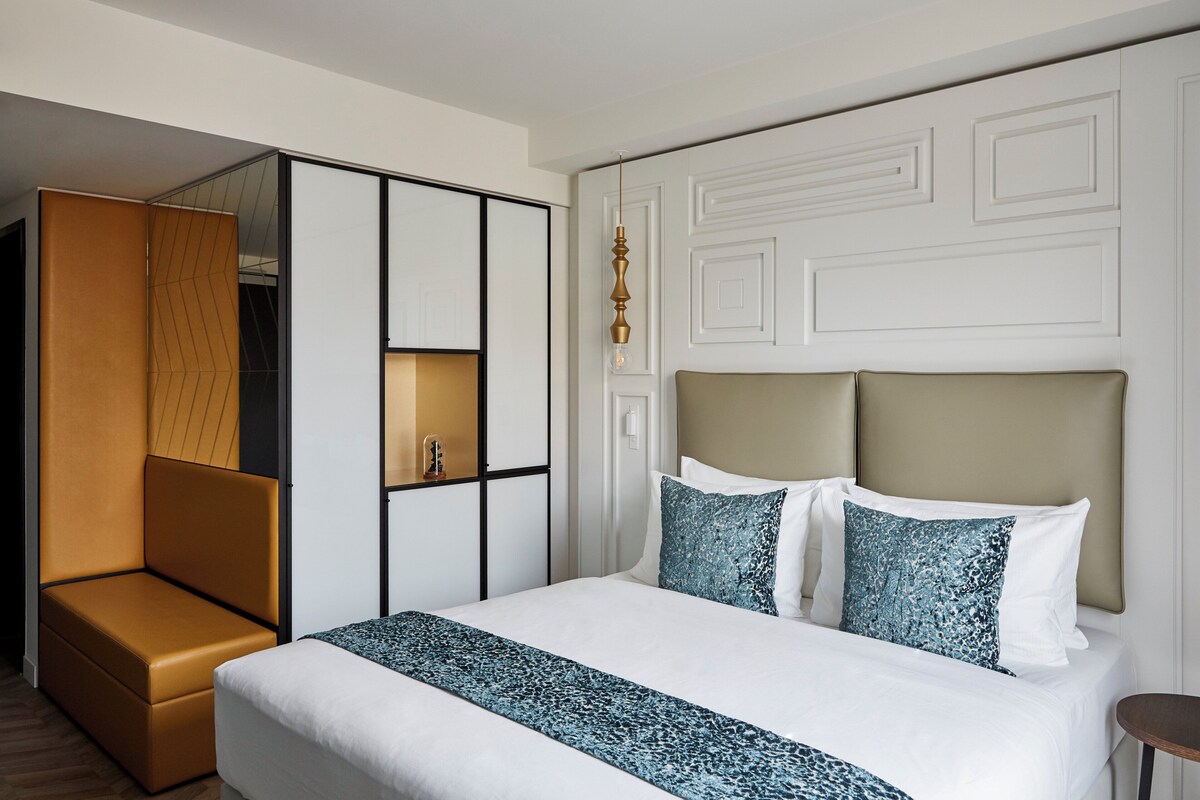 Una habitación de hotel con cama, zona de estar y espejo.