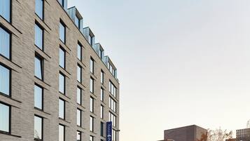 A modern hotel building with a brick facade, multiple windows, and a visible sign for 'hotel INDIGO.'