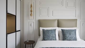 Une chambre d’hôtel bien rangée, avec un lit, deux oreillers, une table de chevet et un luminaire suspendu.