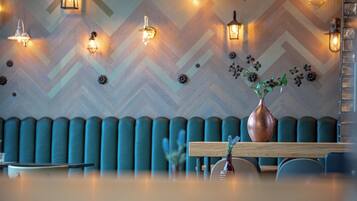 Ein modernes Interieur mit einer Zickzackwand, gepolsterten Sitzmöglichkeiten und einem Holztisch mit einer Blumenvase.
