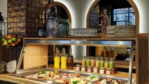 A buffet with a variety of food items, including fruits, cheeses, and meats, as well as a selection of beverages in bottles and glasses. - Hotel Indigo Dresden - Wettiner Platz by IHG (Dresden)