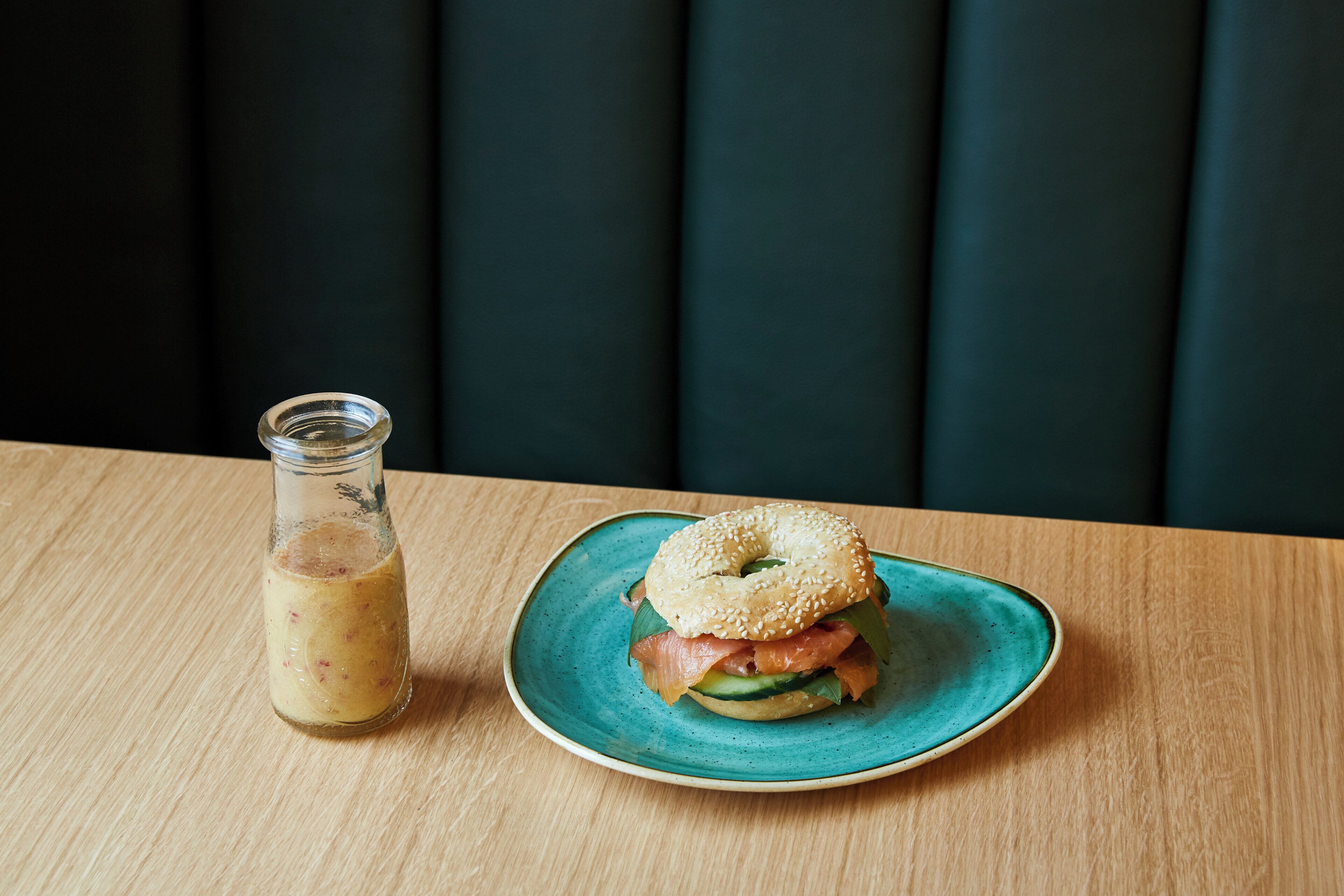 Un sándwich en un plato con una botella al lado.