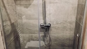 A glass-enclosed shower stall with a handheld showerhead and a wall-mounted faucet. - Aloha House (Formia)