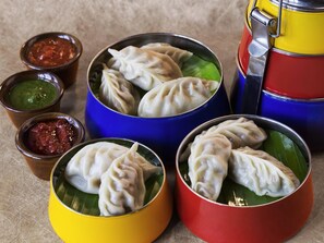 Diverse dumplings in kleurrijke bakjes, vergezeld van kleine schaaltjes met dipsausjes.