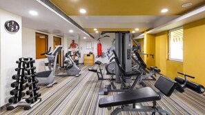 Un gimnasio con equipamiento de ejercicio, un reloj y una ventana.