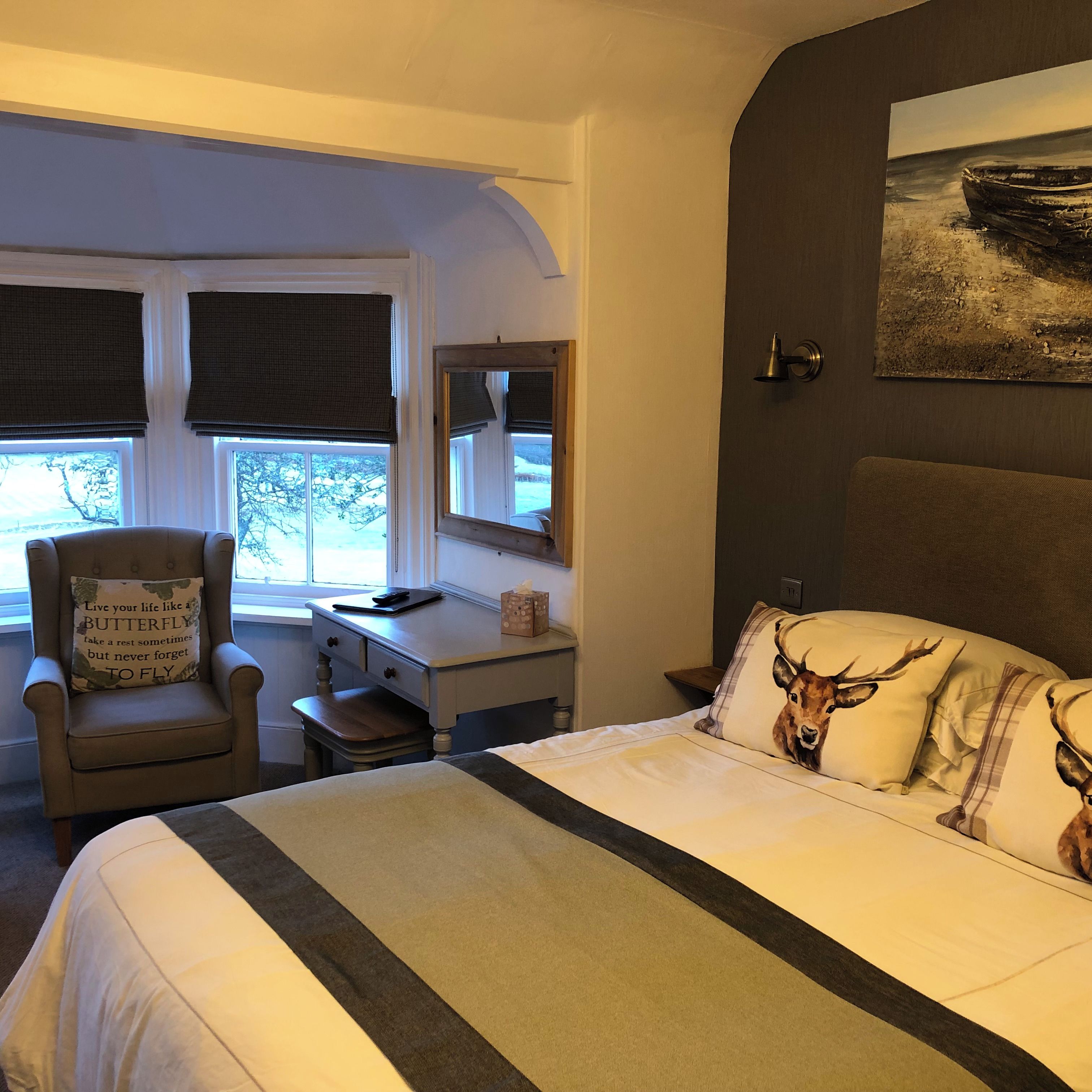 A room with a bed, a desk, a chair, and a window with a view.
