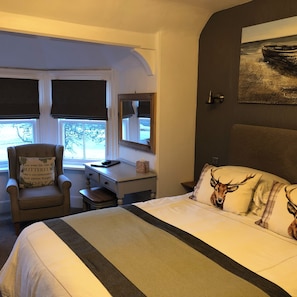 Una habitación con una cama, un escritorio, una silla y ventana con vistas.