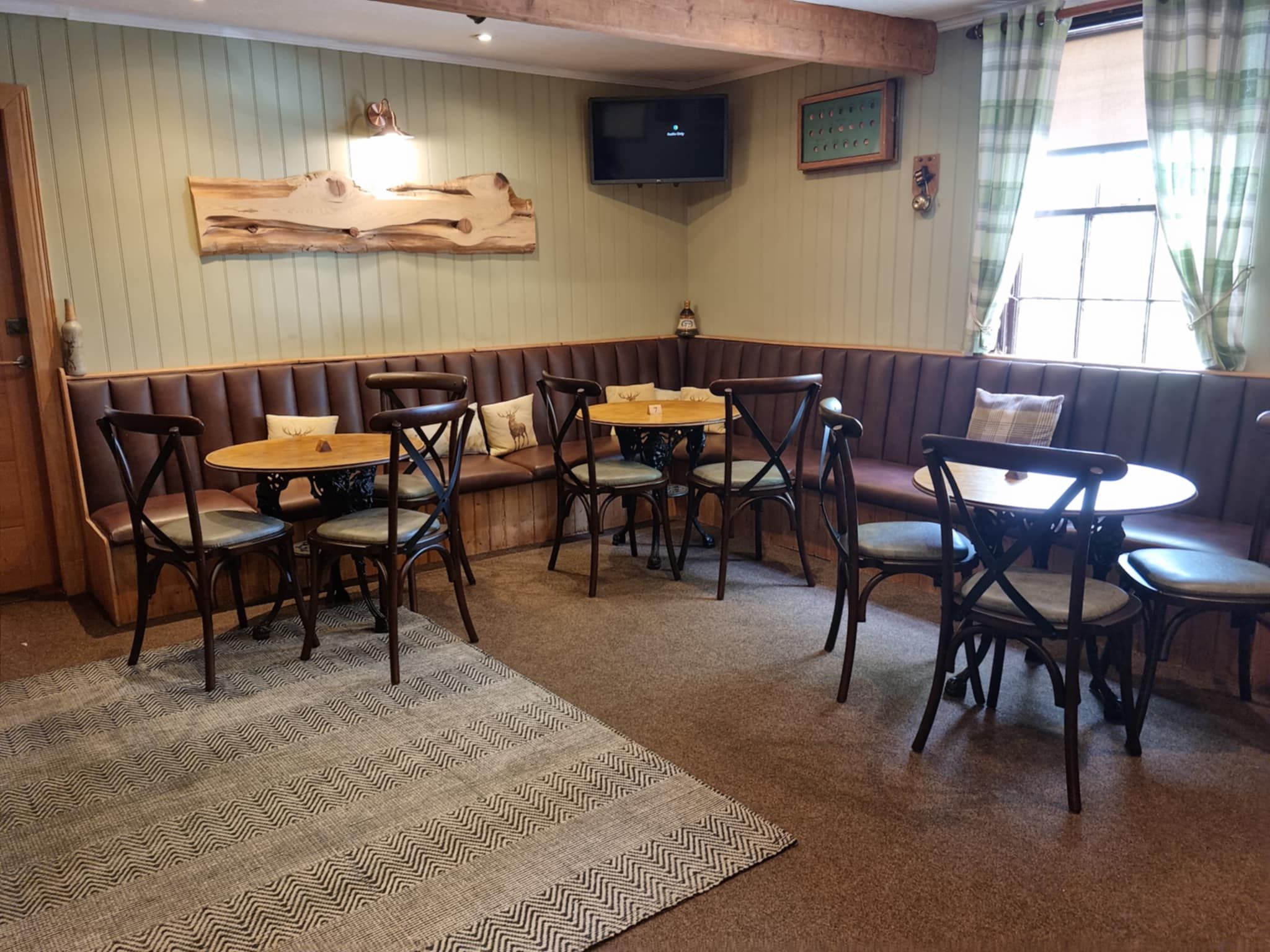 A cozy restaurant interior with a wooden bench seating area, round tables, and chairs.