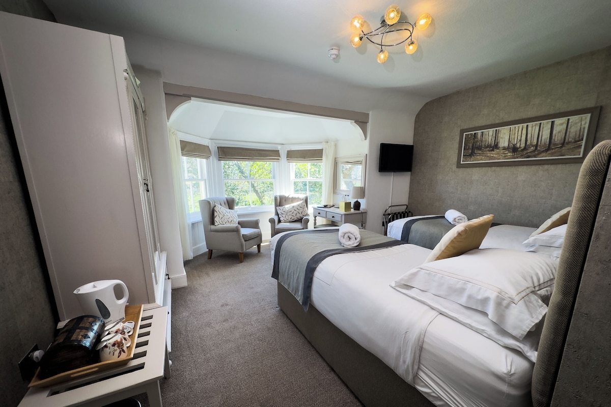 A hotel room with a large bed, a desk, and a view of the outdoors.