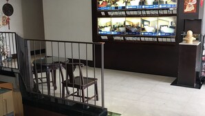 A hotel lobby with a modern chandelier, a staircase with a railing, and a display of rooms on the wall. - Gin Lon Lake motel (New Taipei City)