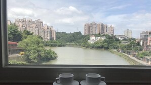 A view from a window overlooking a river with buildings and greenery. - Gin Lon Lake motel (New Taipei City)