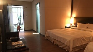 A hotel room with a bed, bedside table, lamp, and a desk with a telephone. - Gin Lon Lake motel (New Taipei City)