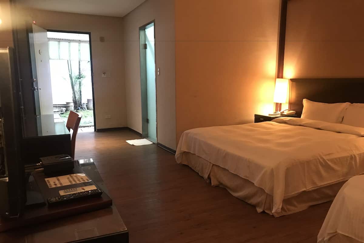 Una habitación de hotel con cama, mesita de noche, lámpara y escritorio con teléfono.