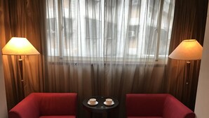A room with two red armchairs, a small round table with two cups, and two lamps on either side of a window with sheer curtains. - Gin Lon Lake motel (New Taipei City)