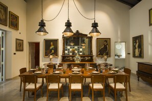 A dining room with a large wooden table set for a meal, surrounded by wooden chairs with cushioned seats. - Monara House (Unawatuna)