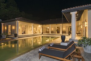 A poolside area with lounge chairs and a large pool. - Monara House (Unawatuna)