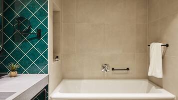Un baño moderno con una bañera, un perchero para toallas y una planta pequeña en el mostrador.