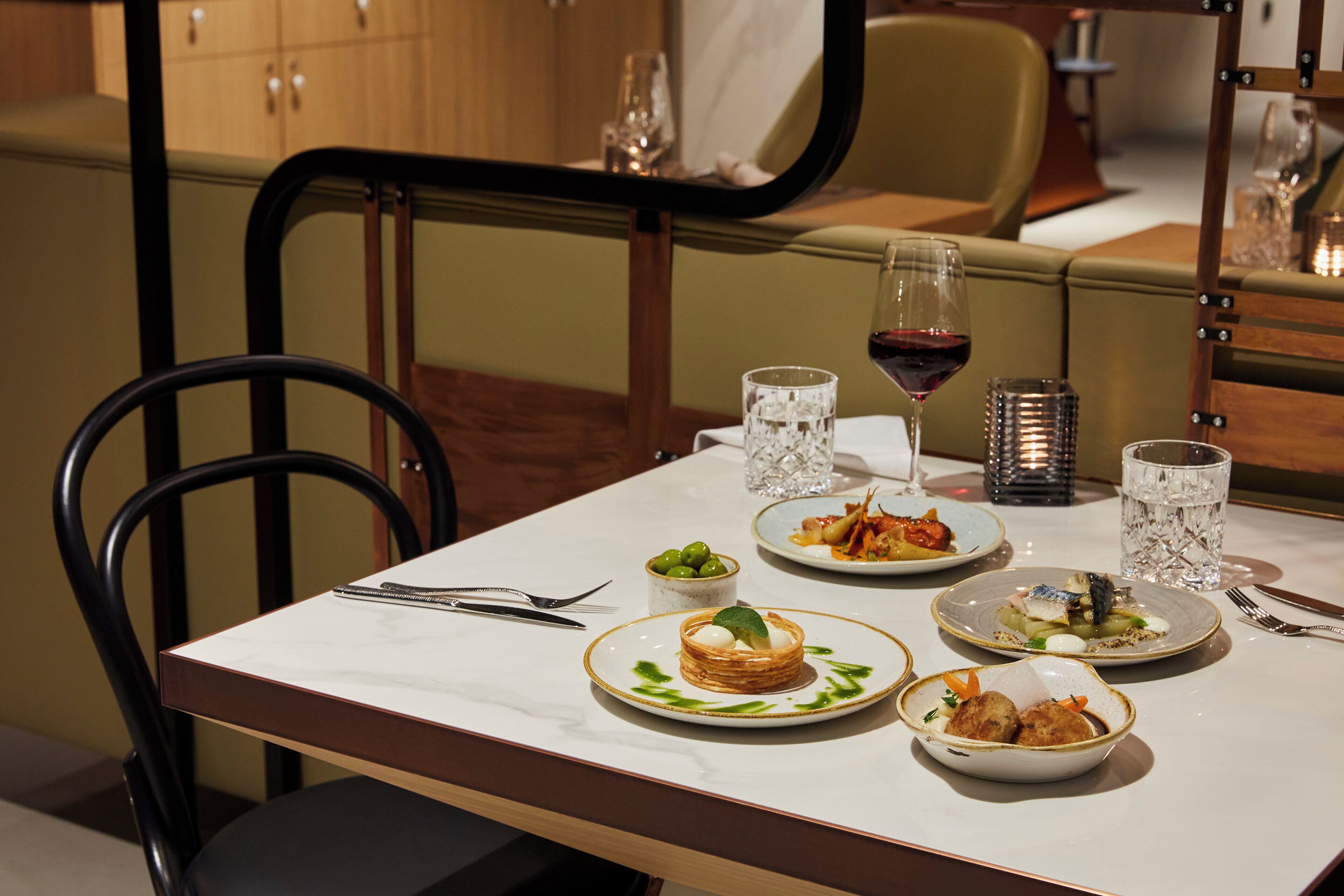 A dining table with plates of food, glasses, and cutlery.