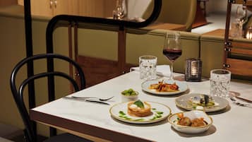 A dining table with plates of food, glasses, and cutlery.
