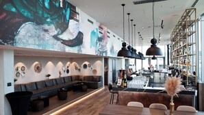 Un bar moderno con una barra larga, asientos y un gran mural en la pared.