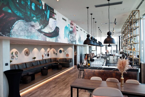 Un bar moderno con una barra larga, asientos y un gran mural en la pared.