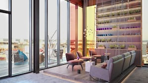 A modern interior with large windows, a seating area with sofas and chairs, and a shelving unit with plants. - Hotel Indigo Berlin - East Side Gallery by IHG (Berlin)