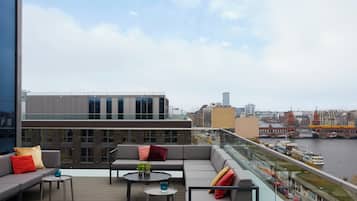 A modern outdoor seating area with a view of a river and cityscape.