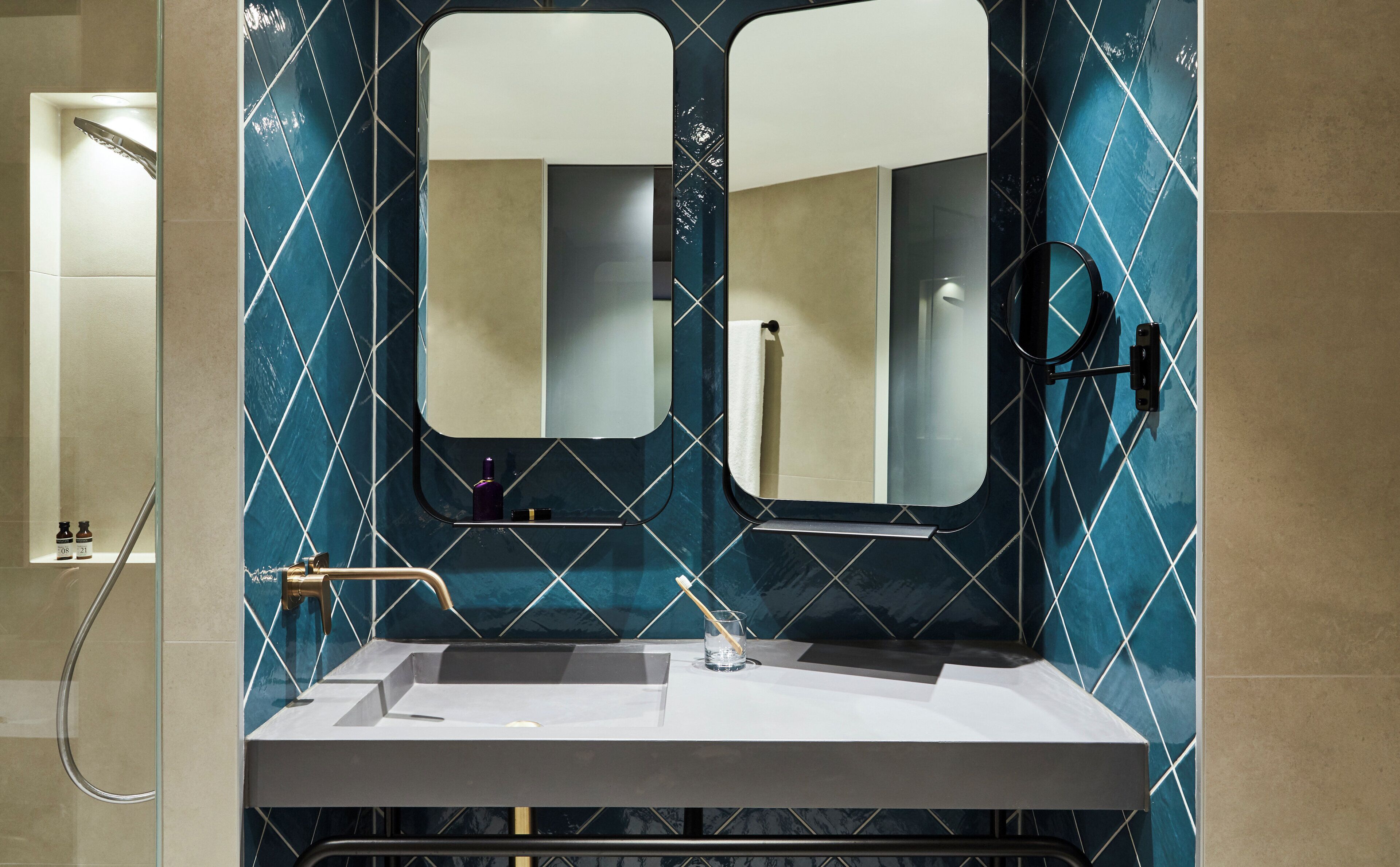 Ein Badezimmer mit Waschbecken, zwei Spiegeln und einem Handtuchhalter.